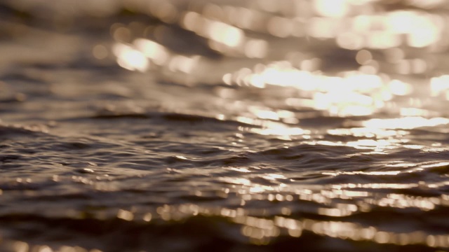 日落时海浪冲向海滩。慢动作海洋白色的水海浪拍击。视频下载