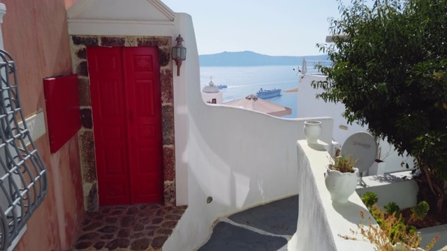 传统的希腊建筑，有一扇亮红色的门，可以看到蓝色的大海。希腊圣托里尼岛,基克拉迪群岛视频素材