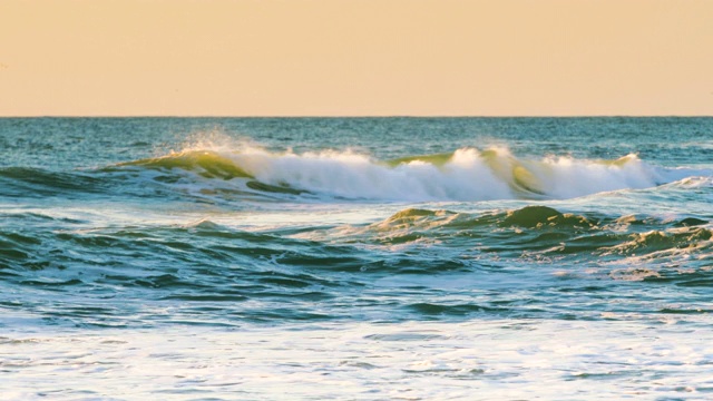 海面上日出，翻滚的海浪向海滩冲去视频素材