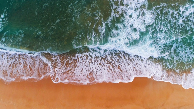 海浪拍打海滩的鸟瞰图。水蓝色的背景视频素材