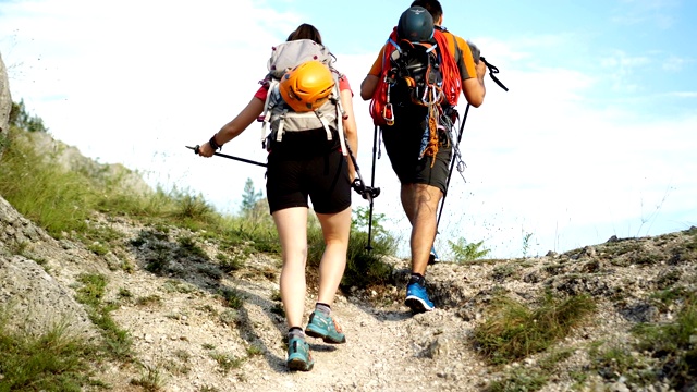 后视图-两个徒步旅行者走在一条穿过一座山的小路上视频素材