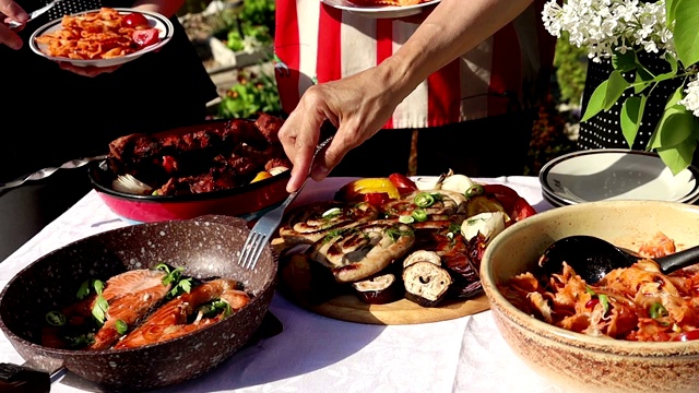 人们在野餐时带着肉，烤肉串和鱼用叉子视频素材