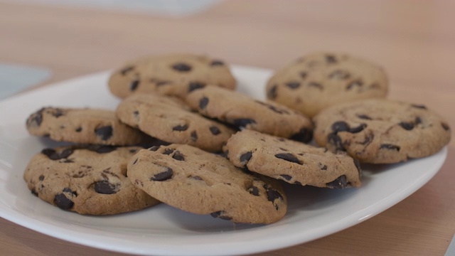 极端特写的盘子与饼干站在桌子上的小白种人孩子的手拿一个饼干。一个面目全非的孩子在家吃着美味的午餐视频素材