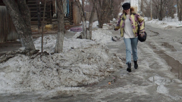 美丽的女孩在路上跑过融化的雪视频下载