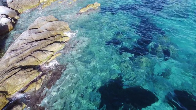 碧绿的海浪在晶莹剔透的海面上溅起白色的岩石。鸟瞰图视频素材