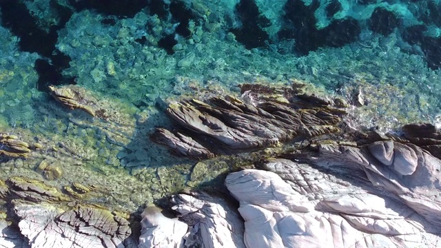 鸟瞰海面上的白色岩石和碧绿清澈的海浪溅在岩石上视频素材