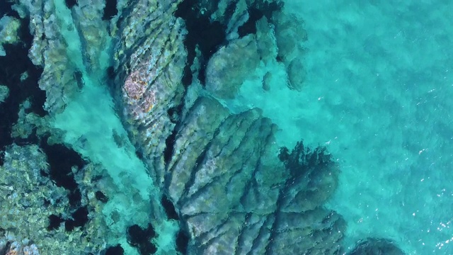 鸟瞰图下的岩石绿松石和水晶清澈的海水。异国情调的热带旅游景点视频素材