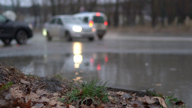 模糊的城市交通在潮湿的道路上在一个雨天的秋天大水坑的道路上视频素材