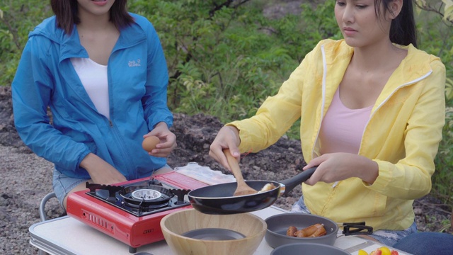 夏天和一群朋友一起开心野餐，一起烹饪食物，男人和女人享受和乐趣露营旅行冒险休闲，一起煎蛋，背包旅行在假期。视频素材