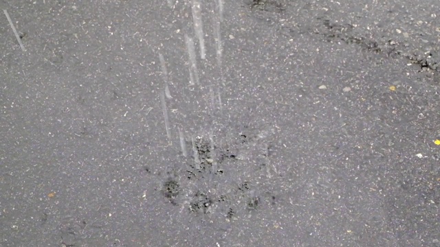 近距离观察雨滴落在街道上，雨滴落在被淹没的道路上视频素材