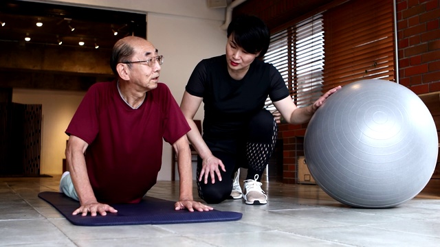 一位年长的男子在听一位女教练的建议做俯卧撑视频素材