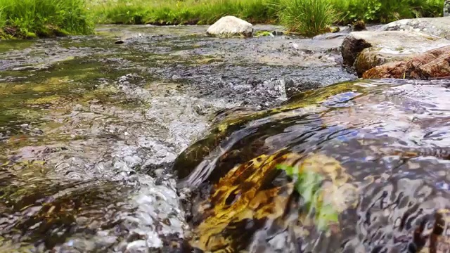 近景山溪与石头和天空反射。流动的河流和光滑的石头。泉水流过石头和绿草视频素材