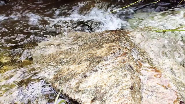 近景山溪与石头和天空的倒影。流动的河流和光滑的石头。泉水流过石头和绿草视频素材