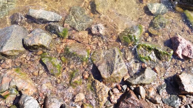 透明水中的石头。水面泛起涟漪。视线从海岸移向大海视频素材