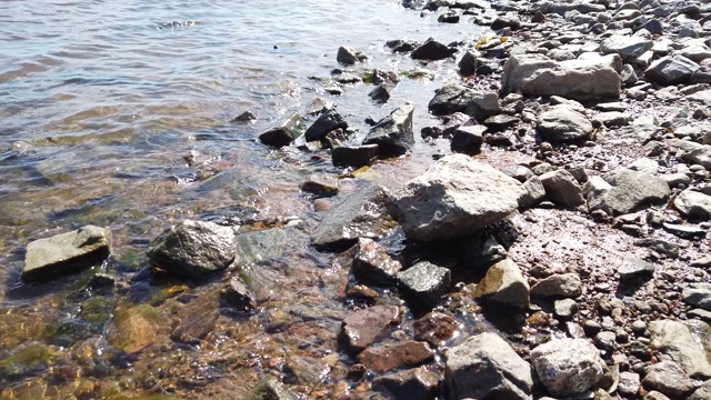 透明水中的石头。海浪逼近多岩石的海岸。涟漪水面视频素材