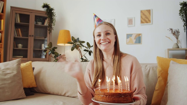 快乐的女人吹蜡烛在蛋糕上庆祝生日的网络电话视频素材