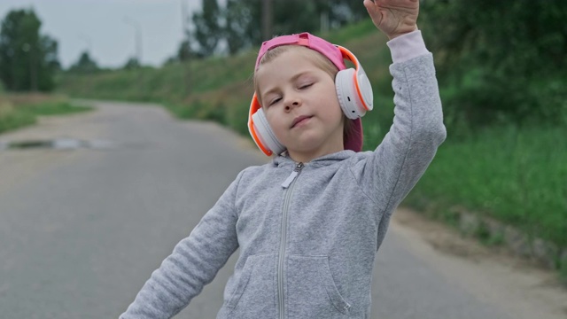 孩子在户外听她最喜欢的歌。快乐的小女孩戴着耳机视频素材