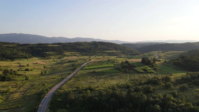 鸟瞰图从上面在绿色的草地和树木之间的山脉的乡村道路周围-自然旅行概念无人机视频在特里西巴在欧洲塞尔维亚在阳光明媚的夏天白天或晚上视频素材