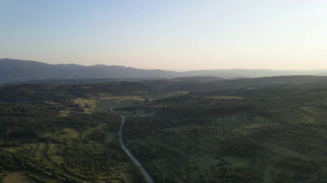 鸟瞰图从上面在绿色的草地和树木之间的山脉的乡村道路周围-自然旅行概念无人机视频在特里西巴在欧洲塞尔维亚在阳光明媚的夏天白天或晚上视频素材