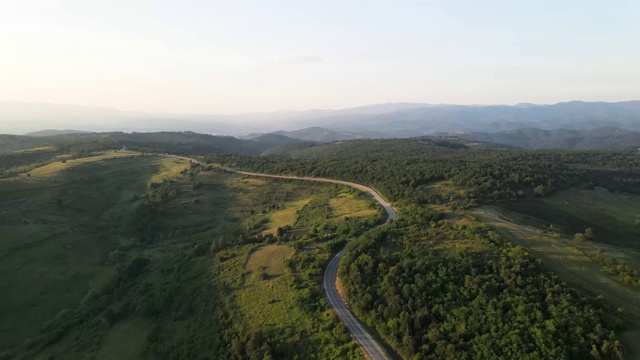 鸟瞰图从上面在绿色的草地和树木之间的山脉的乡村道路周围-自然旅行概念无人机视频在特里西巴在欧洲塞尔维亚在阳光明媚的夏天白天或晚上视频素材