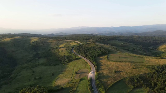 鸟瞰图从上面在绿色的草地和树木之间的山脉的乡村道路周围-自然旅行概念无人机视频在特里西巴在欧洲塞尔维亚在阳光明媚的夏天白天或晚上视频素材