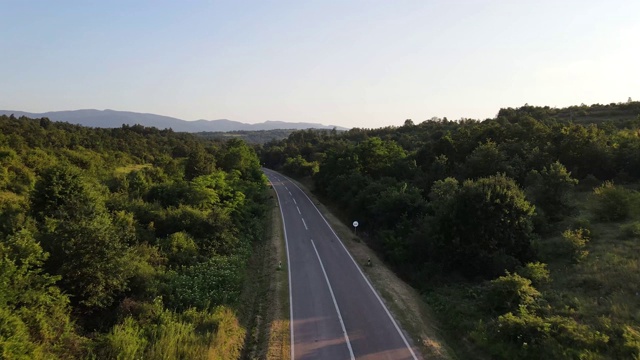 鸟瞰图从上面在绿色的草地和树木之间的山脉的乡村道路周围-自然旅行概念无人机视频在特里西巴在欧洲塞尔维亚在阳光明媚的夏天白天或晚上视频素材