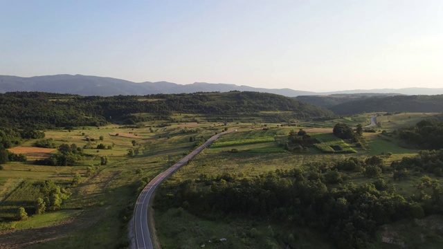 鸟瞰图从上面在绿色的草地和树木之间的山脉的乡村道路周围-自然旅行概念无人机视频在特里西巴在欧洲塞尔维亚在阳光明媚的夏天白天或晚上视频素材