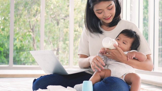 年轻的亚洲妇女用奶瓶喂养新生儿。视频素材