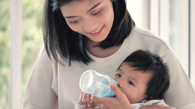 年轻的亚洲妇女用奶瓶喂养新生儿。视频素材