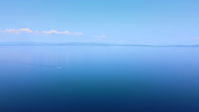 在远处的蓝天下，在蔚蓝的大海上航行的小船。鸟瞰图视频素材