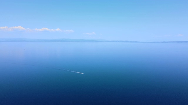 在远处的蓝天下，在蔚蓝的大海上航行的小船。鸟瞰图视频素材