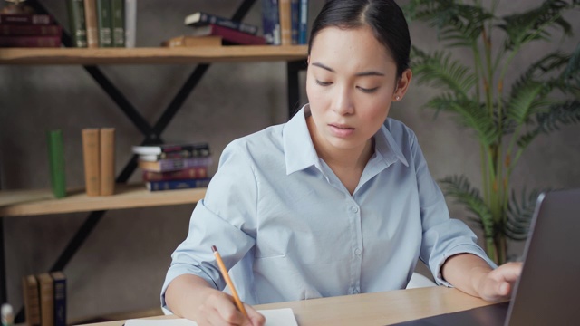 近距离拍摄的亚洲女学生用笔记本电脑做作业视频素材