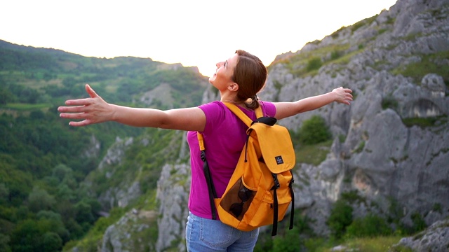 女人徒步旅行者在山顶张开双臂视频素材