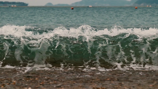 蓝色的海浪拍打着沙滩和砾石海岸的慢镜头视频素材