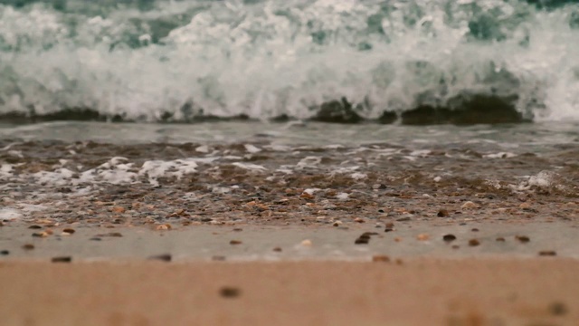 蓝色的海浪拍打着沙滩和砾石海岸的慢镜头视频素材