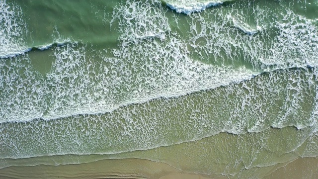 海浪或海浪拍岸。泡沫状的海浪翻滚着涌向沙滩。视频素材