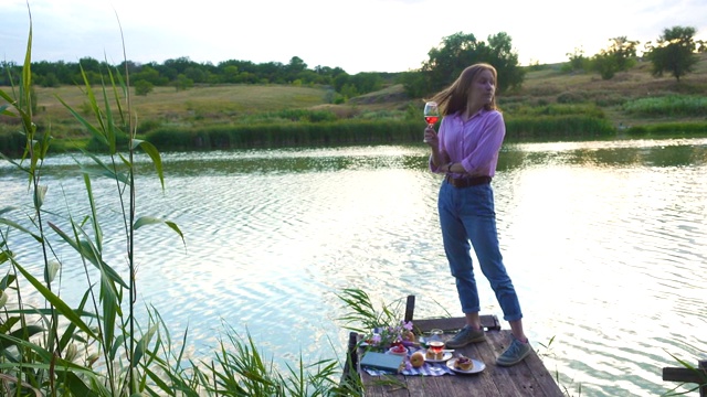 女孩享受野餐在一个木制码头上在一个闪亮的夏天河岸视频素材