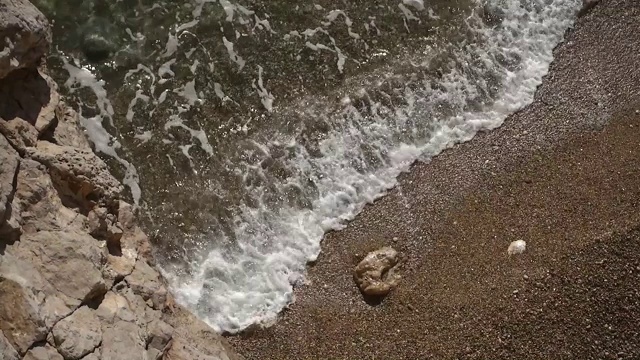 海滩上的岩石和翻滚的海浪溅起水花视频素材