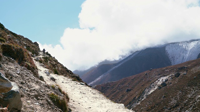 4K镜头的壮观的高海拔山谷，斜坡上升的两侧和背包客上去视频素材