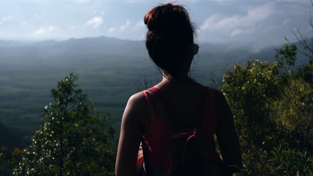 一个年轻的女人正在山顶上看风景。慢动作视频下载