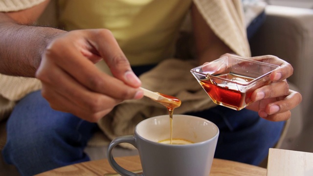 生病的年轻人在家往热茶里加蜂蜜视频素材