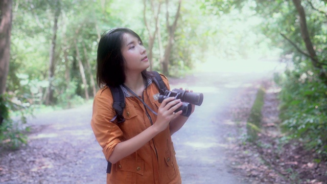 快乐美丽的年轻亚洲女人冒险使用双目在丛林寻找休闲，女孩徒步旅行有背包观光度假在森林露营，假期和夏天的概念。视频素材