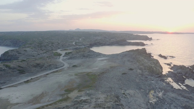 鸟瞰图的岩石海岸与空的道路在日落视频下载