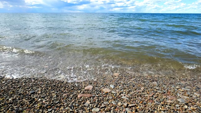 海浪翻滚在宽阔的海滩与石头在夏天白天视频素材