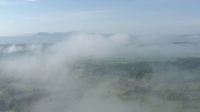 通过4K航拍视频，在田野和树林上空降下雾气视频素材