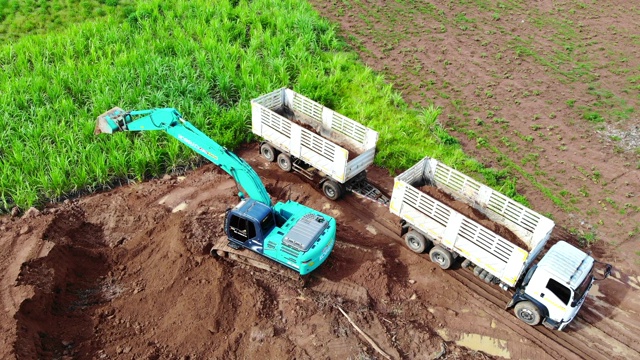 挖土机将泥土装进卡车，然后由卡车运送泥土出售。视频素材