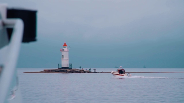 在海上带着波浪航行到古代灯塔的游艇视频素材