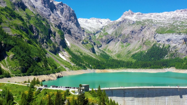 大坝在一座山中间，背景是一个蓝色的湖。可再生能源和电力技术场景。美丽的景观鸟瞰图与无人机4k视频素材