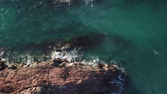 鸟瞰图的海浪打破在蓝色的海洋岩石。海浪对美丽的海滩鸟瞰图无人机4k拍摄。鸟瞰图的海浪撞击一个空的石头岩石悬崖从上面。视频素材