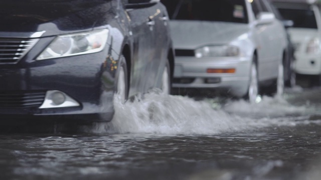 在道路上行驶的汽车带有地表水。交通雨水和道路积水。视频素材